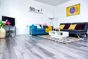 a living room with wooden floors and a blue couch at The Pent House - Lushio Apartments in Northampton