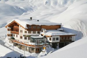 Un edificio con la neve sopra di esso nella neve di Gasthof Valluga a Sankt Christoph am Arlberg