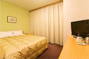 a hotel room with a bed and a flat screen tv at Highness Hotel Kurume in Kurume