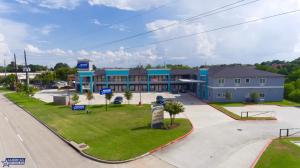 a large blue building with a park in front of it at Americas Best Value Inn Houston Willowbrook in Houston