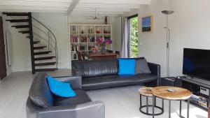 uma sala de estar com um sofá de couro preto e uma mesa em Buitenplaats Schouwen em Burgh Haamstede