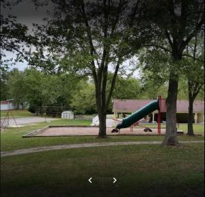 a playground with a slide in a park with trees at Round Top Two-Bedroom Cottage 8 in Gettysburg +3 photos