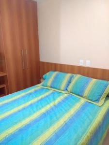 uma cama com lençóis listrados azul e amarelo num quarto em Serra Park Flat Service - Rio Quente Esplanada apartamento inteiro roupas de cama a parte em Rio Quente