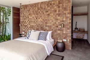 a bedroom with a brick wall and a bed at Villa Nonnavana - 12-minute walk to Batu Bolong Beach in Canggu