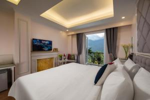 a bedroom with a large white bed and a window at Sapa Praha Hotel in Sa Pa