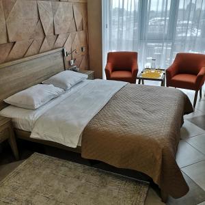 a bedroom with a large bed and two chairs at ACCOMMODO192 in Dnipro