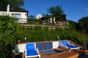 - deux chaises bleues assises sur la terrasse d'une piscine dans l'établissement Ferieneinrichtungen Haus am Stein, à Königstein