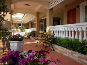 a porch with a bench on a house with flowers at Nuntiya Terrace in Udon Thani