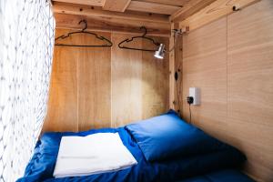 a blue bed in a room with a wooden wall at Uzu House in Shimonoseki