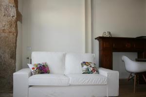 un sofá blanco con almohadas florales en la sala de estar. en Fita Hotel Rural, en Sequeros