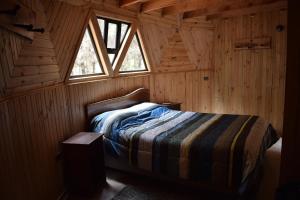 um quarto com uma cama num chalé de madeira em Domos Nelkewue em Santa Bárbara