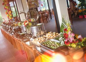 a long buffet of food on a table with flowers at Sang Như Ngọc Resort in Chau Doc