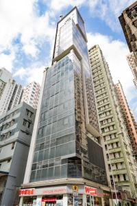 a tall glass building in a city with tall buildings at Mia Casa Hotel in Hong Kong