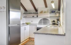 Una cocina con gabinetes blancos y un refrigerador de acero inoxidable. en Awesome Home In Hvide Sande With Sauna, en Bjerregård