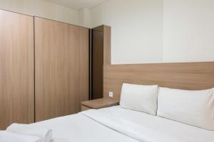 ein Schlafzimmer mit einem Bett und einem hölzernen Kopfteil in der Unterkunft Cozy Studio Apartment at Brooklyn Alam Sutera By Travelio in Dongkal Dua + 6 Fotos