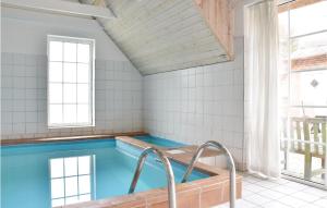 a swimming pool with blue water in a room with windows at Beautiful Home In Ulfborg With 6 Bedrooms, Wifi And Indoor Swimming Pool in Øhuse