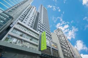 a tall building with a green sign in front of it at Hotel Ease Mong Kok in Hong Kong