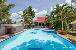 a swimming pool in front of a house with palm trees at Long Beach Inn in Sam Roi Yot