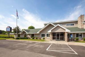 a building with an american flag in a parking lot at AmericInn by Wyndham Northfield in Northfield