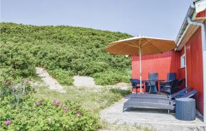 a patio with chairs and an umbrella next to a building at Holiday Home Lodbergsvej Ringkøbing Iii in Søndervig