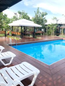 a swimming pool with two white lounge chairs next to it at T'Luck House Resort in Haad Chao Samran