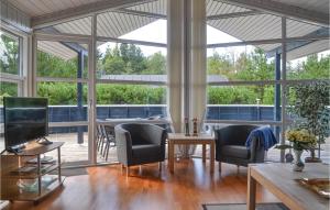 a living room with chairs and a table and windows at Holiday Home Fyrrekrogen Vi in Lønne Hede