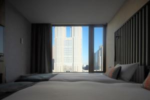 a bedroom with a bed with a large window at THE KNOT TOKYO Shinjuku in Tokyo