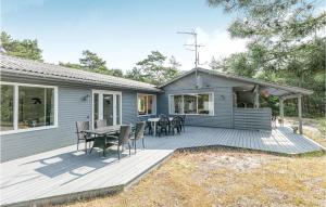 a blue house with a deck with a table and chairs at Holiday Home I Klitterne Nexø I in Spidsegård