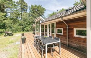 una terraza de madera con mesa y sillas en una casa en Rubinsen Skovhuse, en Hasle