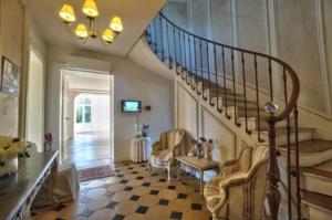 a living room with a staircase with chairs and a table at Château de Bel Ebat in Nozay