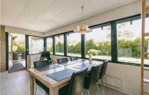 uma sala de jantar com mesa, cadeiras e janelas em Amazing Home In Gudhjem With 3 Bedrooms And Wifi em Gudhjem