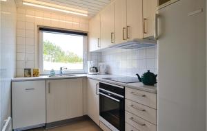 a kitchen with a stove and a sink and a refrigerator at Holiday Home Arvidvej Denmk Xii in Bjerregård