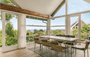 a dining room with a table and chairs and windows at Stunning Home In Svaneke With House Sea View in Svaneke