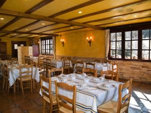 a dining room with white tables and chairs and windows at Posada Calera in Valle De Villaverde