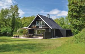 une maison avec un toit noir sur un champ vert dans l'établissement 3 Bedroom Beautiful Home In Blvand, à Blåvand