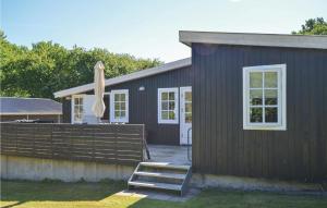 a brown house with a deck and an umbrella at Two-Bedroom Holiday Home In Balle in Vester Balle +12 photos
