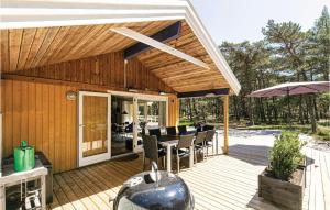 una terraza de madera con mesa, sillas y sombrilla en Pet Friendly Home In Nex With Wifi, en Spidsegård