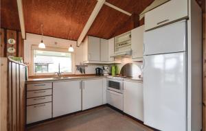 a kitchen with white cabinets and a white refrigerator at Holiday Home Lakolk Iv Denmark in Bolilmark