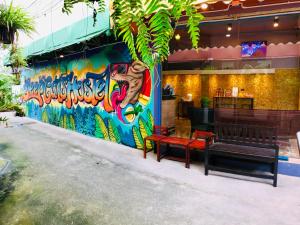een bankje voor een gebouw met een muurschildering bij SleepCatsHostel in Bangkok