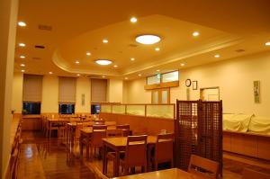 una sala da pranzo con tavoli e sedie in legno di Hotel Route-Inn Fukui Owada a Fukui