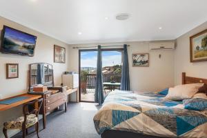 a bedroom with a bed and a desk and a computer at Anchors Aweigh - Adult & Guests Only in Narooma