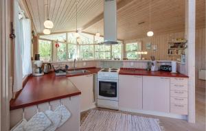 Beautiful Home In Grlev With Kitchen في Reersø: مطبخ كبير مع أجهزة بيضاء وجدران خشبية