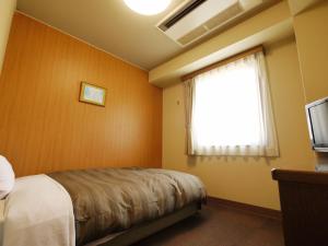 a bedroom with a bed and a window and a television at Hotel Route-Inn Takasaki Eki Nishiguchi in Takasaki