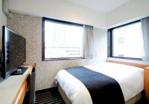 a bedroom with a bed and a tv and two windows at APA Hotel Tokyo Ojima in Tokyo