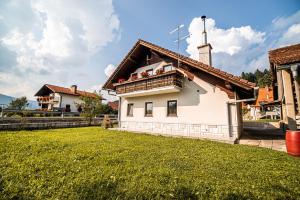 a white house with a tower and a grass yard at Holiday Home Mountain View in Ljubno