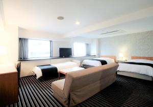 東京にあるアパホテル〈東京大島〉のベッド2台とソファが備わるホテルルームです。