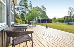 エーベルトフトにあるAmazing Home In Ebeltoft With 3 Bedrooms, Sauna And Wifiの木製デッキ(椅子、テーブル付)