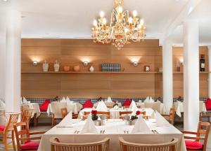 ein Esszimmer mit weißen Tischen und einem Kronleuchter in der Unterkunft Hotel Agneshof Nürnberg in Nürnberg