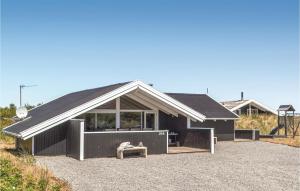 a black house with a pitched roof with a bench at Three-Bedroom Holiday Home In Hvide Sande in Bjerregård +11 photos