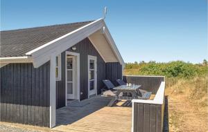BjerregårdにあるAwesome Home In Hvide Sande With Kitchenの木製デッキ(テーブル付)が備わる黒い建物